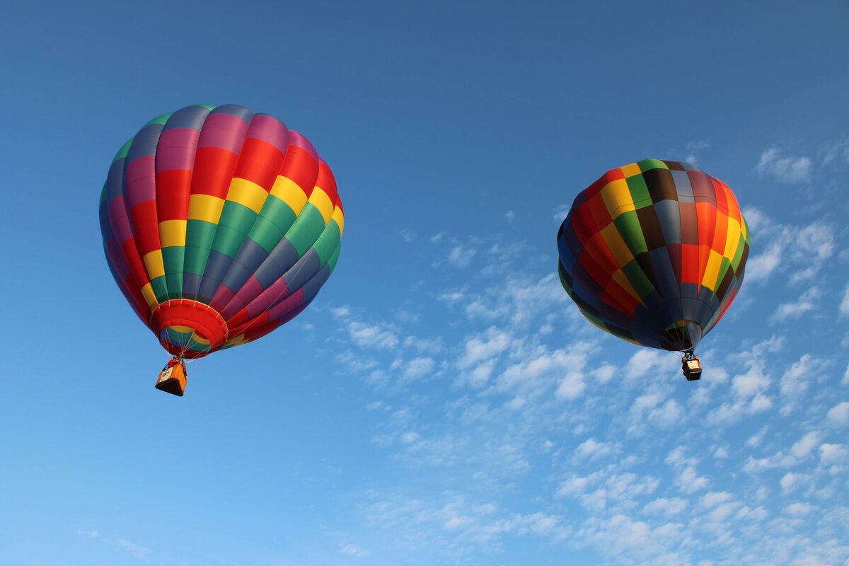 Two hot air balloons floating in an open blue sky