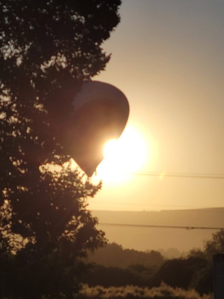 A hot air balloon illuminated by sunrise