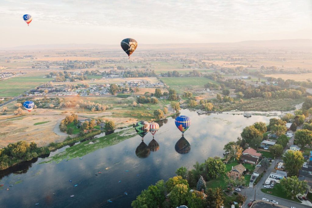 Hot air balloons floating above the Yakima River and Prosser valley at dawn